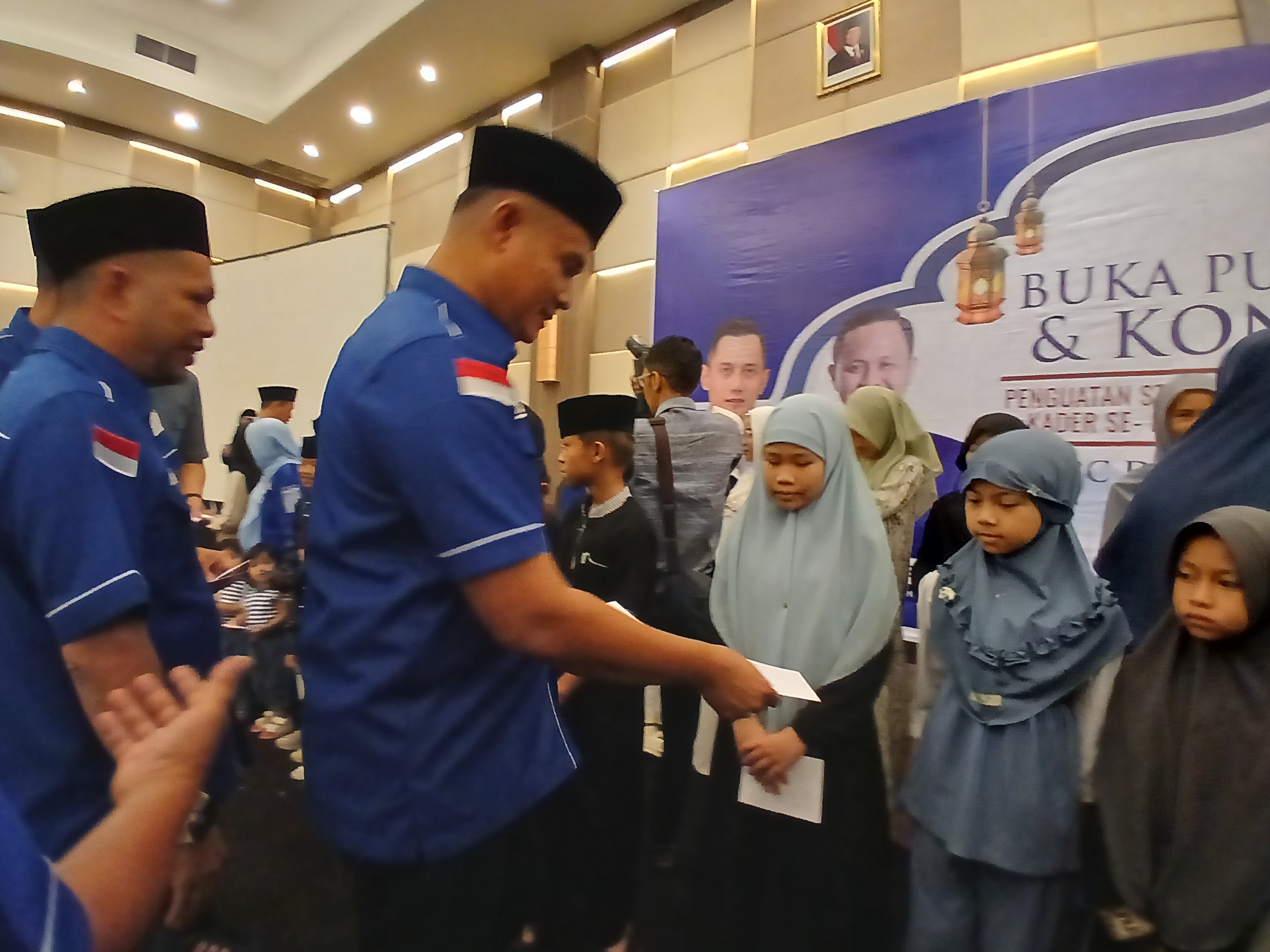 Pengurus Partai Demokrat Pekanbaru menyerahkan santunan kepada anak yatim piatu dalam acara buka bersama di Hotel Pangeran Pekanbaru, Minggu (8/3/2026). Foto: Surya/Riau1.