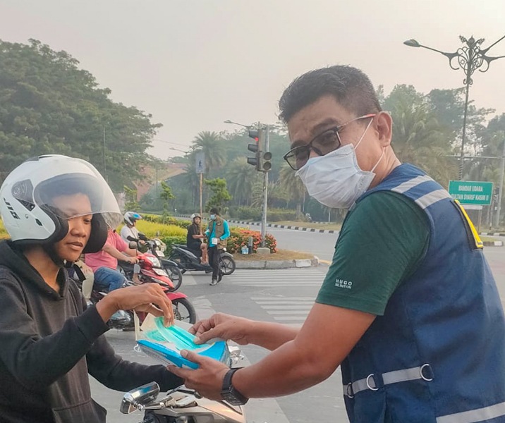 Ketua Bidang Sosial Gonjong Limo Pekanbaru Joni Ariyanto bersama relawan lainnya membagikan masker kepada para pengendara di Simpang Tiga. Foto: Istimewa.