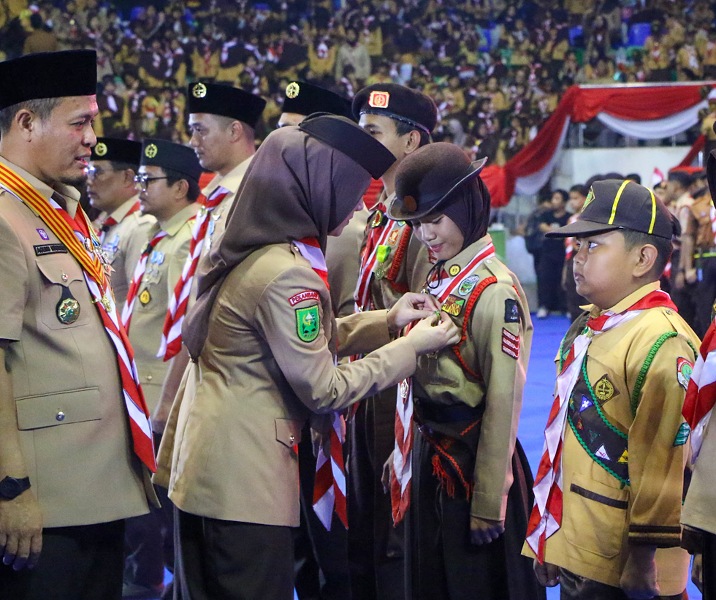 Ketua Kwarcab Gerakan Pramuka Kota Pekanbaru Sulastri memasangkan lencana kepada anak-anak Pramuka karena telah mengikuti Jambore Nasional. Foto: Istimewa.